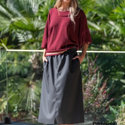Mulher com camisola bordeaux, saia preta longa, sapatos bordeaux e sunglasses