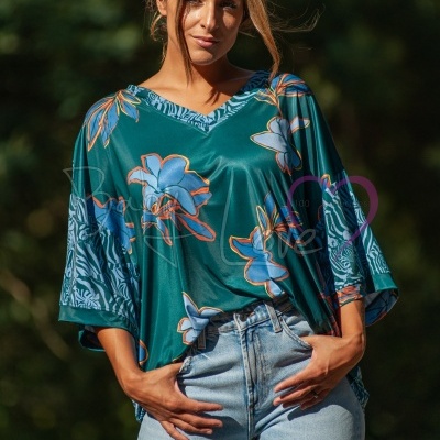 T-shirt verde com padrão floral azul e laranja e calças de ganga claras num ambiente exterior