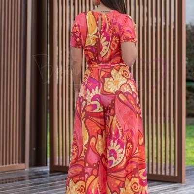 Vestido comprido floral em tons quentes visto de costas com salto alto laranja