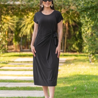 Vestido preto comprido com atilho na cintura e mangas curtas usado por mulher num jardim