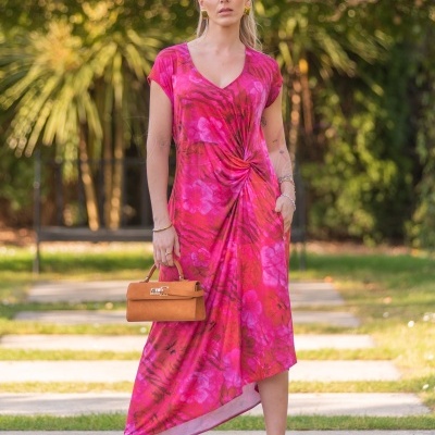 Mulher com vestido rosa floral assimétrico e bolsa castanha ao ar livre