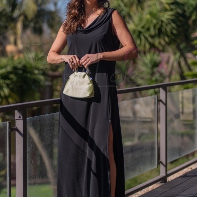 Mulher com vestido preto longo, sandálias pretas e bolsa clara ao ar livre