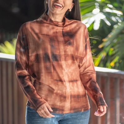 Túnica feminina castanha com padrão tie-dye usada por mulher sorridente ao ar livre