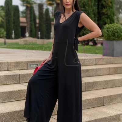 Mulher a usar macacão preto fluido e sapatos vermelhos em escadas exteriores