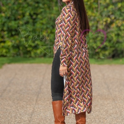 Cardigã comprido geométrico castanho, branco, vermelho e preto com botas castanhas em cenário exterior