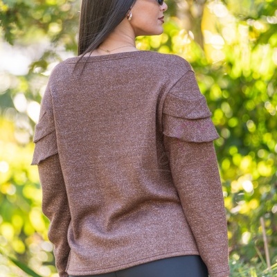Mulher de costas com camisola castanha brilhante e óculos escuros ao ar livre