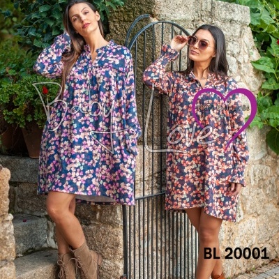 Duas mulheres com vestidos florais ao ar livre junto a portão de ferro e pedra.