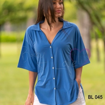 Mulher a usar camisa azul com botões brancos e shorts brancos ao ar livre