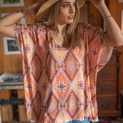 Blusa larga com padrão geométrico em várias cores e chapéu de palha
