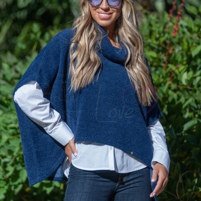 Mulher com capa azul, camisa branca e óculos de sol ao ar livre