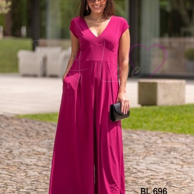 Macacão rosa feminino com decote V e bolsos, usado com sandálias e clutch preta, em ambiente exterior