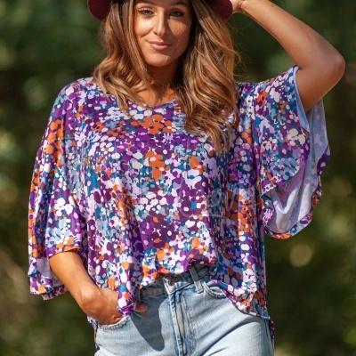 top floral colorido roxo e laranja com mangas largas e jeans claro