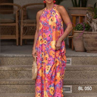 Mulher com vestido longo floral colorido e acessórios na escadaria