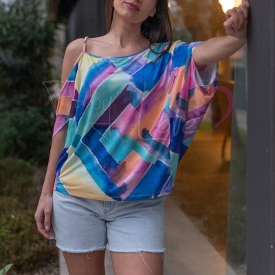 Mulher a usar blusa colorida e calções de ganga claros perto de uma janela de vidro