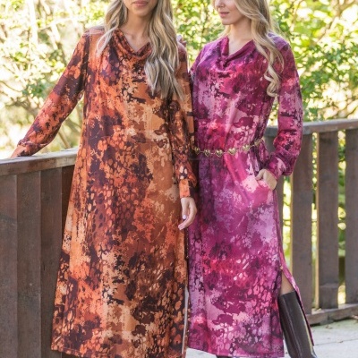 Duas mulheres com vestidos compridos estampados andando ao ar livre com botas altas