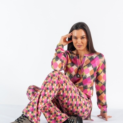 Mulher sentada a usar conjunto colorido geométrico e botas castanhas com sola preta