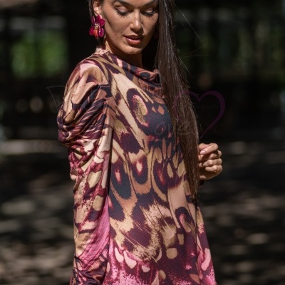Blusa de padrão abstrato em tons castanhos, rosa e roxo com modelo em cenário ao ar livre