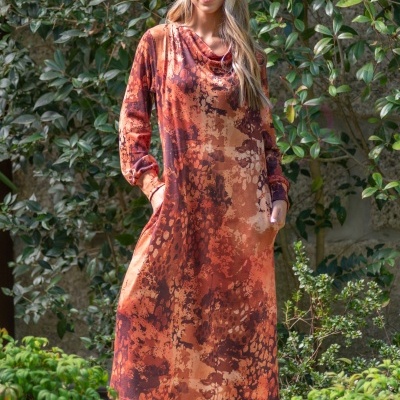Vestido comprido feminino padrão abstrato em tons de laranja e castanho com mangas e bolsos, usado com botas castanhas em jardim
