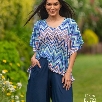 Mulher com túnica estampada zig-zag azul e calças culotte azul-escuro em jardim exterior