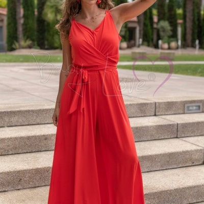 Mulher com vestido longo vermelho, óculos de sol e sandálias, em degraus exteriores