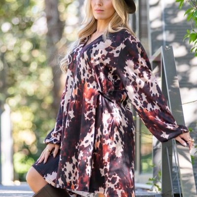 Mulher com vestido animal print castanho e chapéu castanho em escadas ao ar livre