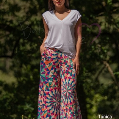 Modelo com túnica branca e calças largas coloridas com padrão geométrico
