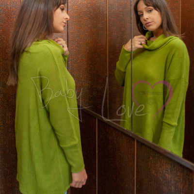 Mulher com camisa verde de malha olhando para o espelho num ambiente com painéis de madeira escura