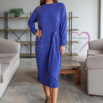 Vestido azul canelado com nó decorativo usado por mulher em sala de estar