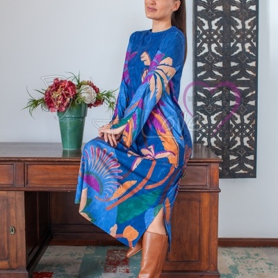 Mulher sentada em mesa de madeira com vestido azul colorido e botas castanhas