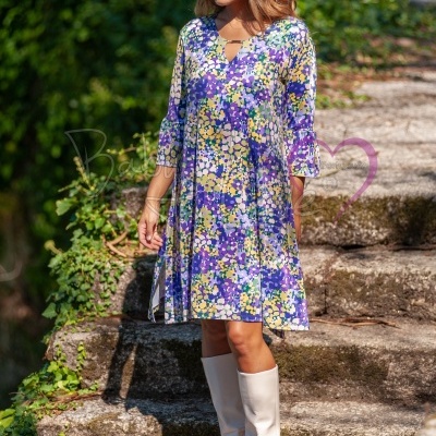 Vestido floral roxo, amarelo e branco com botas brancas em escadaria de pedra exterior