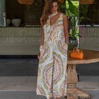 Macacão comprido branco com padrões circulares coloridos e mala laranja sobre mesa de madeira