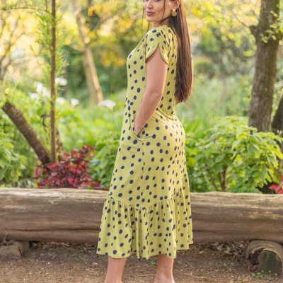 Vestido midi amarelo com bolinhas pretas e sandálias de salto transparente ao ar livre