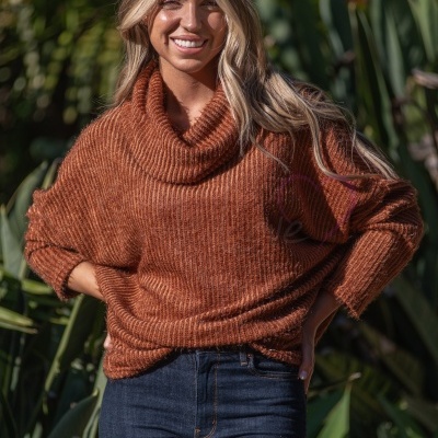 Mulher com camisola castanha de malha e calças de ganga azuis ao ar livre
