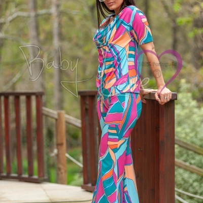 Conjunto túnica e calças coloridas com padrão geométrico usado por mulher com óculos de sol e sandálias em madeira exterior.