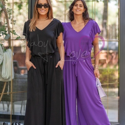 Duas mulheres com macacões fluídos em preto e roxo em ambiente com porta de vidro