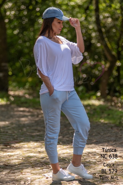 Mulher vestindo túnica branca e calças azul claro ao ar livre