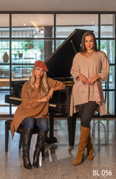 Duas mulheres com suéteres castanho e bege junto a um piano de cauda em sala moderna.