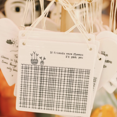 Placas de cerâmica branca com ilustrações e texto penduradas em suporte de madeira