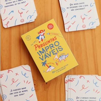 Jogo de cartas Perguntas Improváveis com cartas em português sobre mesa de madeira