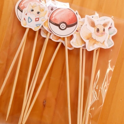 Palitos de madeira com recortes de Pokémon embalados em plástico