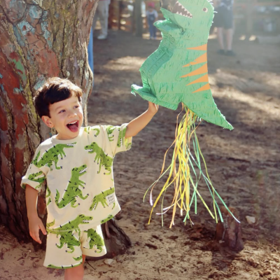 Camisola e calções de criança estampados com dinossauros e piñata dinossauro verde ao ar livre