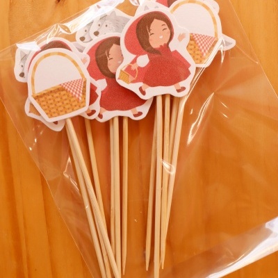 Palitos de madeira com figuras de menina de capuz vermelho e cesta em saco plástico