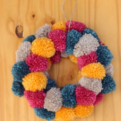 Guirlanda colorida de pompons de lã pendurada em madeira clara