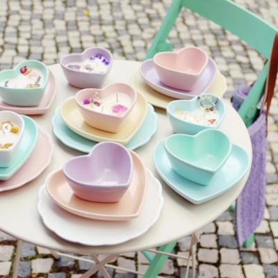Pratos e tigelas em forma de coração de cerâmica em cores pastel sobre mesa branca