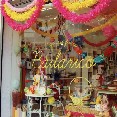 Montra de loja com decoração festiva colorida e itens decorativos visíveis