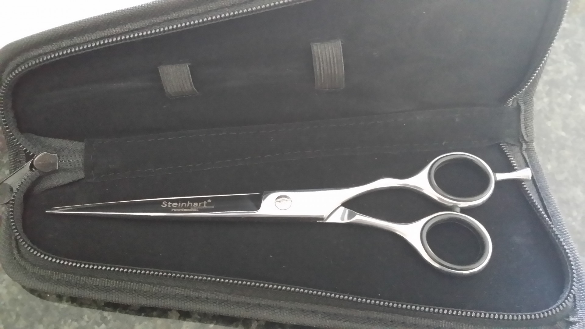 Tesoura de corte prateada dentro de estojo preto acolchoado