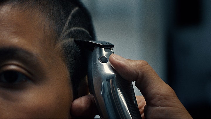 Máquina de cortar cabelo prateada a aparar cabelo com padrão de linhas raspadas