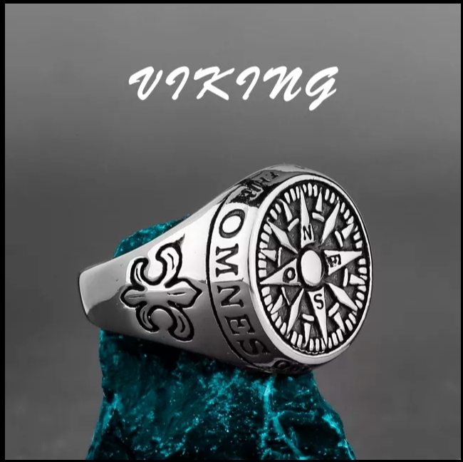 Anel prateado com bússola e símbolos, sobre pedra azul