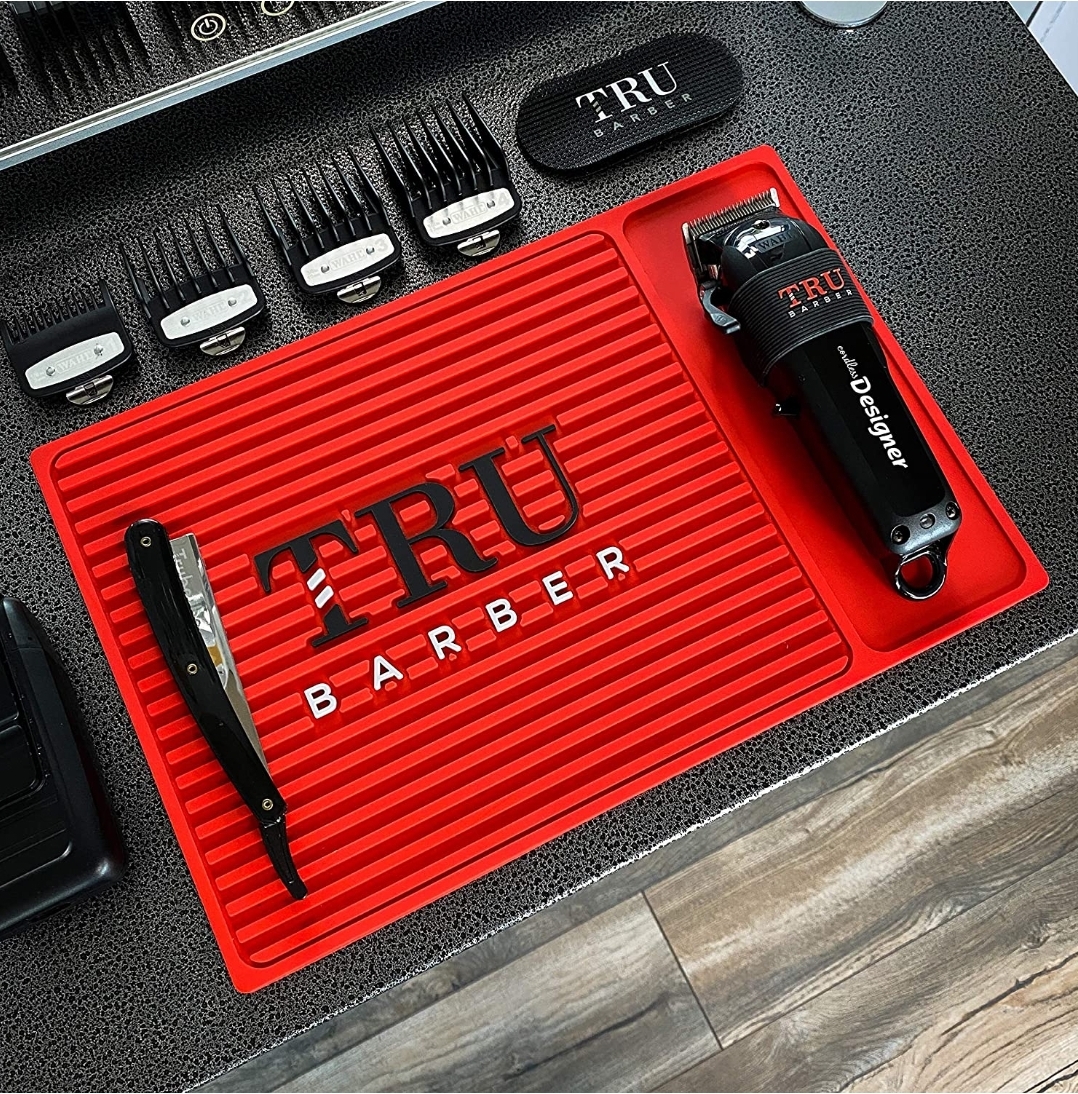 Ferramentas de barbearia TRU BARBER numa base vermelha com máquina, navalha e pentes.