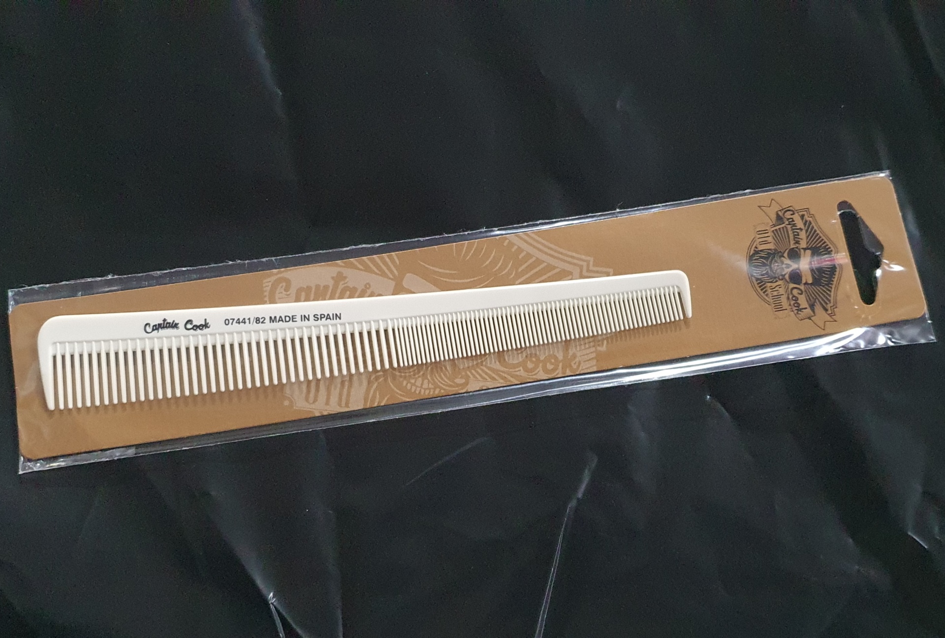 Pente branco para cabelo na embalagem castanha sobre fundo preto